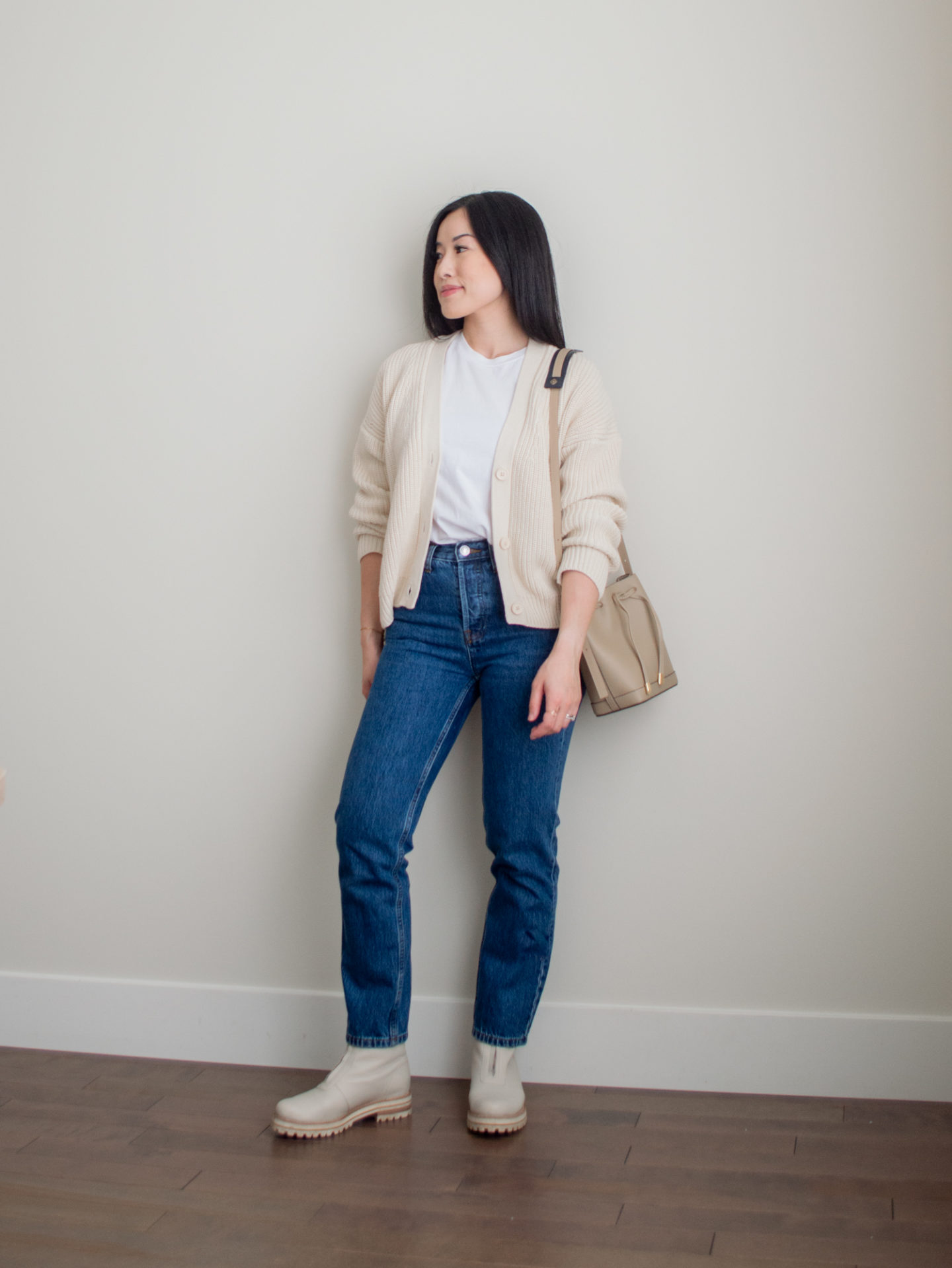 Sharon of Her Simple Sole is showcasing an outfit from her September outfit roundup, featuring a basic white T-Shirt, blue straight leg jeans, a cream cardigan, a taupe bucket bag and cream chunky boots | minimalist outfits | simple outfit ideas