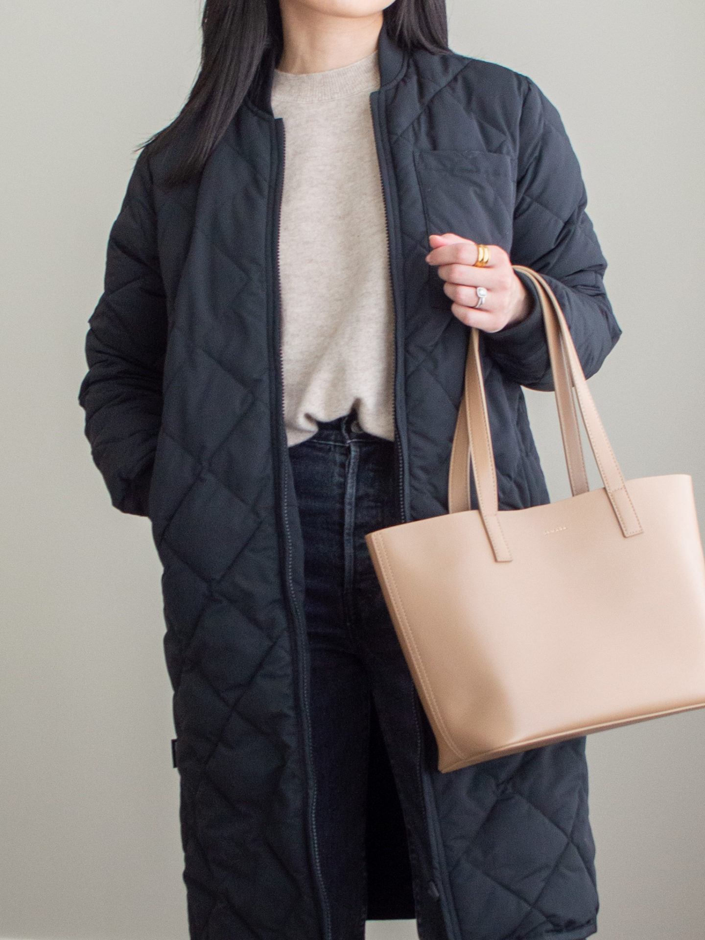 Close-up detailed outfit shot of Sharon of Her Simple Sole wearing a beige cashmere sweater, grey straight leg jeans, black maxi bomber jacket, brown tote bag | minimalist style | bomber jacket style