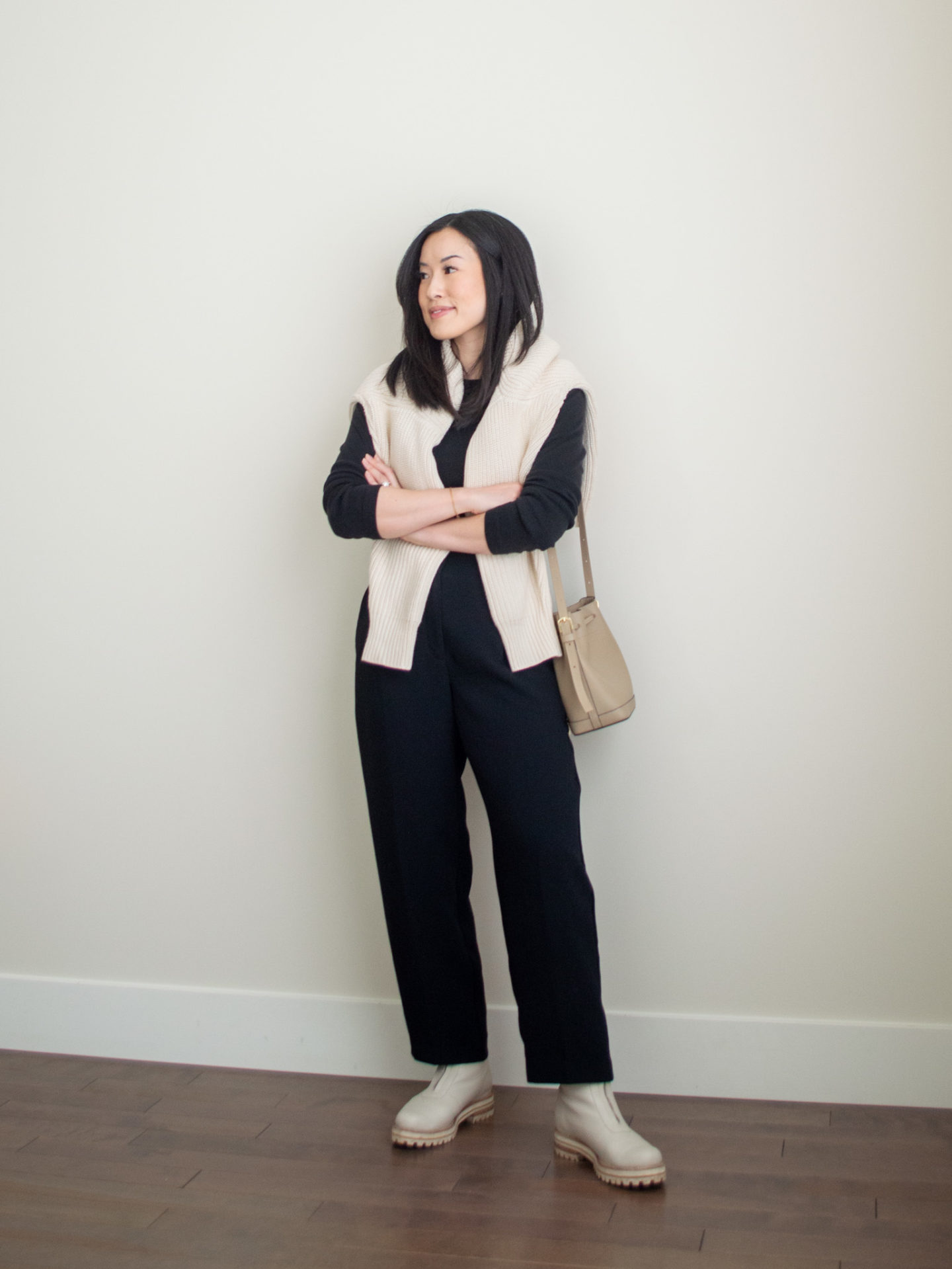 Sharon of Her Simple Sole is showcasing 1 of 10 fall outfits featuring a cream cotton cardigan over the shoulders, black long sleeve top, black cropped trousers, taupe bucket bag and cream chunky boots | minimalist outfits | simple outfit ideas | easy fall outfit