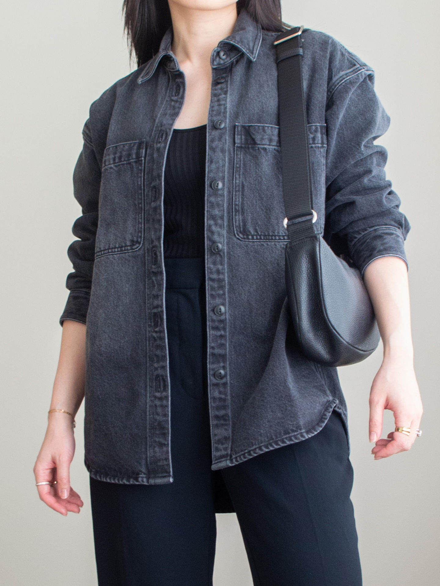 Close-up detailed outfit shot of Sharon of Her Simple Sole wearing a black ribbed tank top, grey oversized denim jacket, black wide-leg pants, black slouchy bag and gold ring | denim shirt look | monochrome black outfit | minimal style