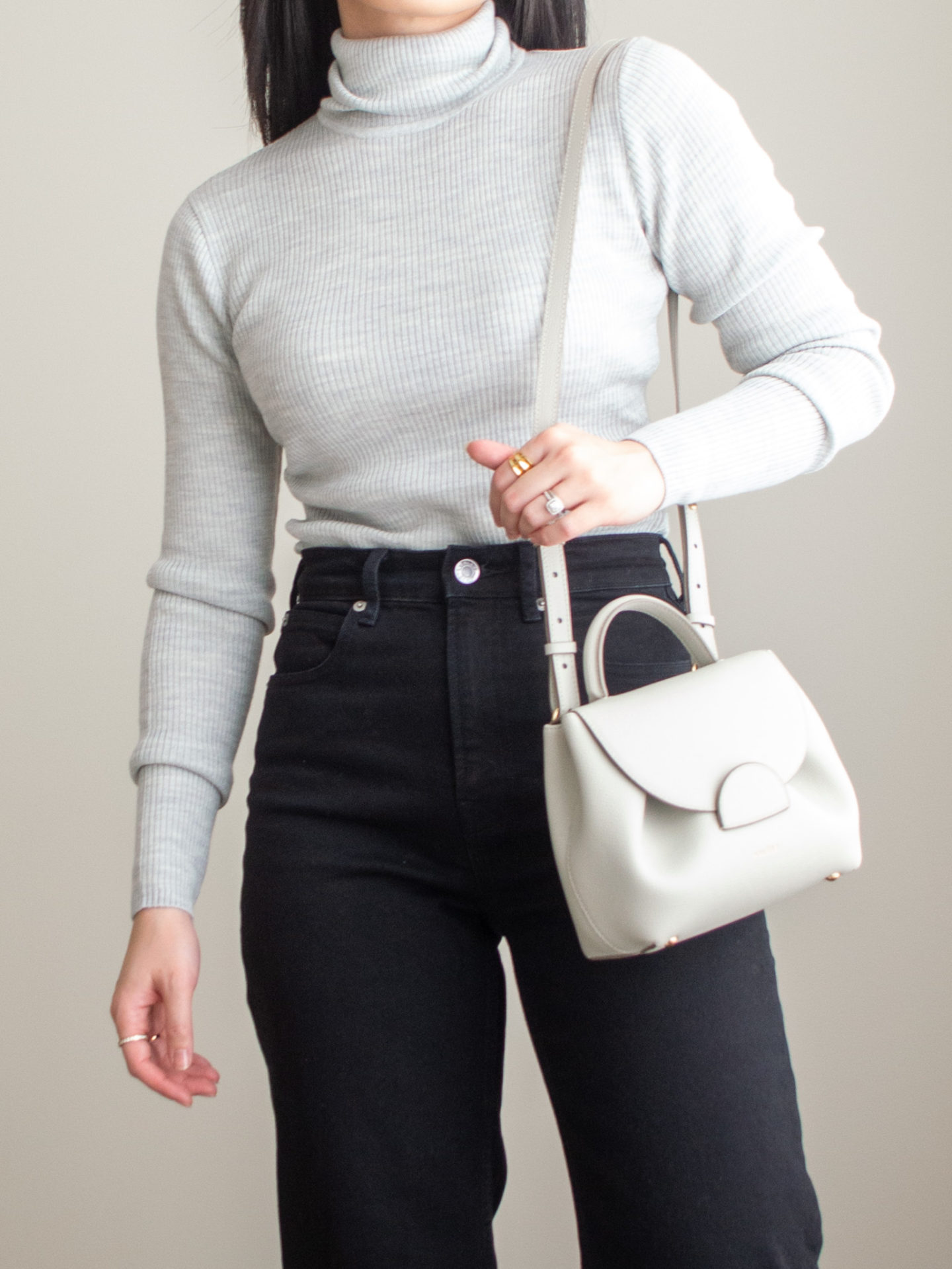 Close-up detailed outfit shot of Sharon of Her Simple Sole wearing a grey merino wool turtleneck top, black straight leg jeans, off-white crossbody bag and gold ring | minimalist outfits | simple outfit ideas | minimalist styles