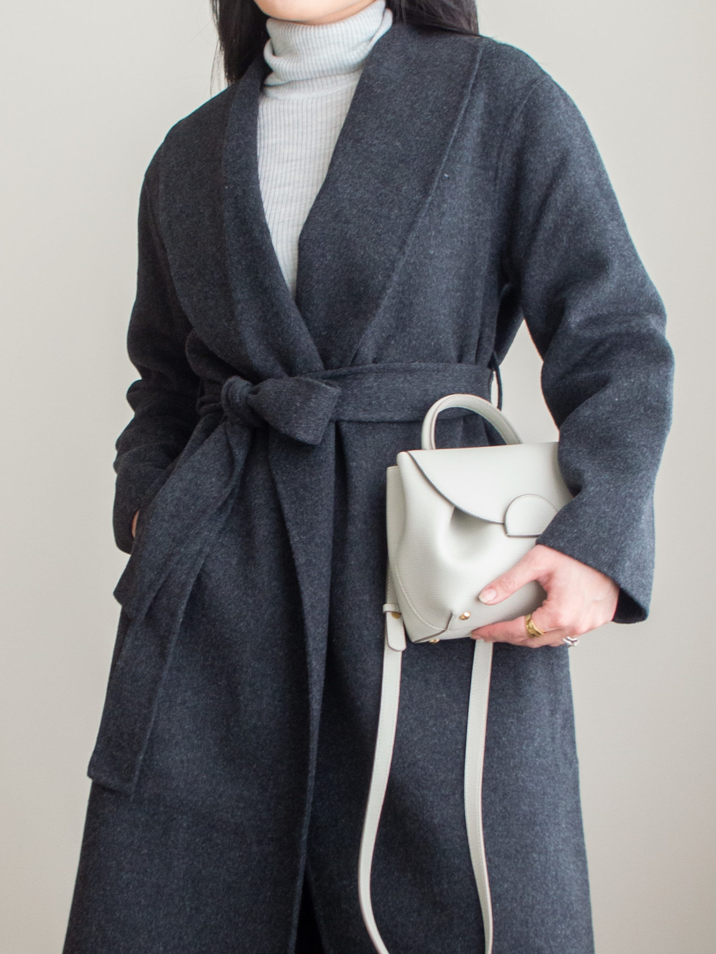 Close-up detailed outfit shot of Sharon of Her Simple Sole wearing a grey merino wool turtleneck top, grey wool robe coat, black straight leg jeans, off-white crossbody bag and gold ring | fall coat idea | minimal style