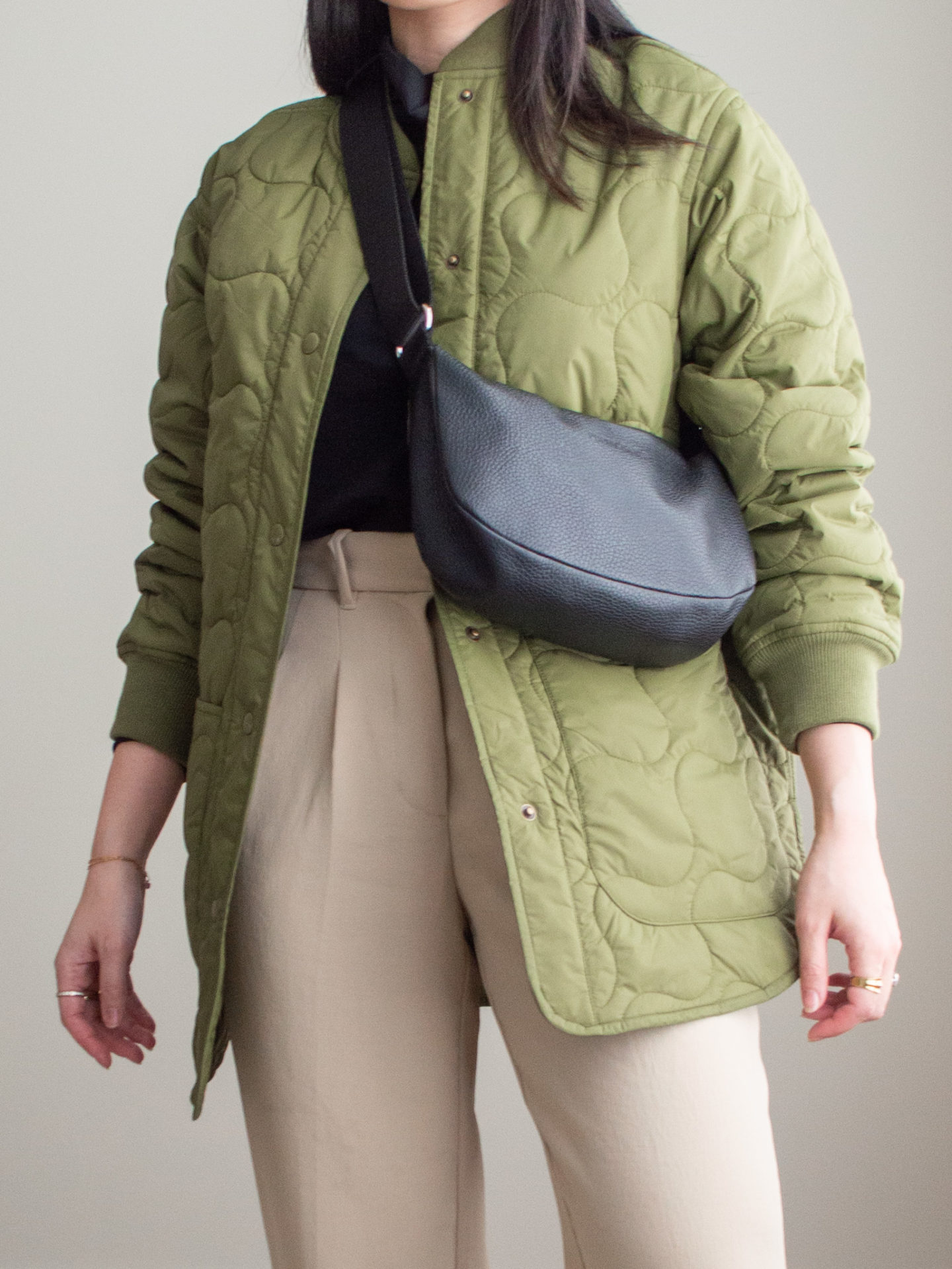 Close-up detailed outfit shot of Sharon of Her Simple Sole wearing a green bomber jacket, black turtle neck top, tan cropped trousers, black slouchy bag, gold chunky ring | minimalist outfits | simple outfit ideas | minimalist styles