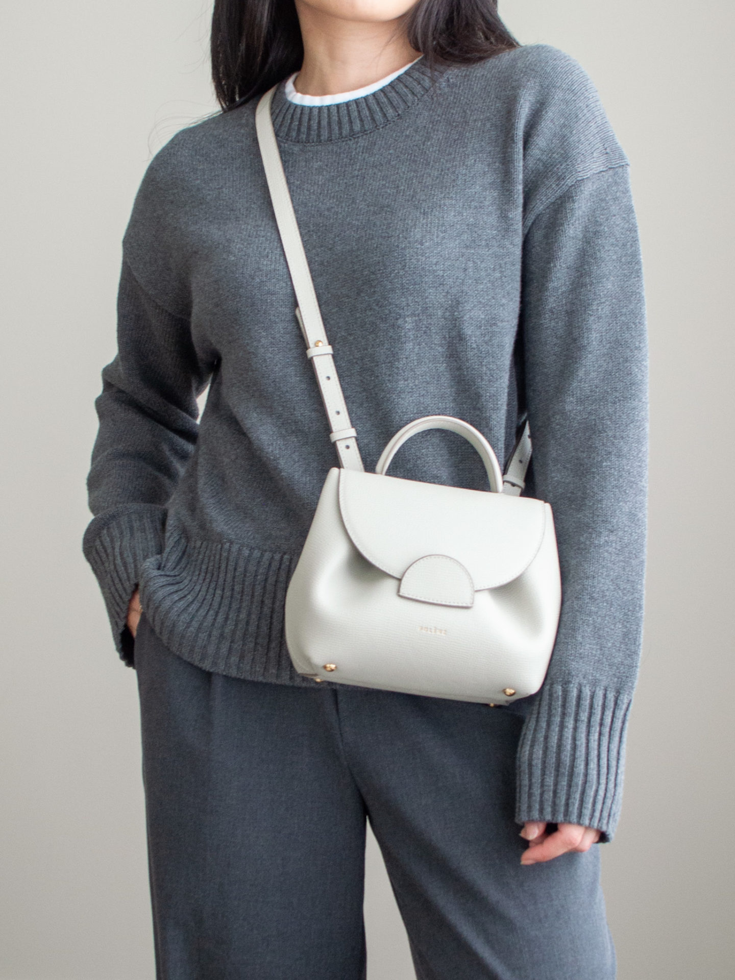 Close-up detailed outfit shot of Sharon of Her Simple Sole wearing a grey cotton sweater, white t-shirt underneath, grey wide-leg pants, off-white crossbody bag | minimal style, cotton sweater look, fall lookbook