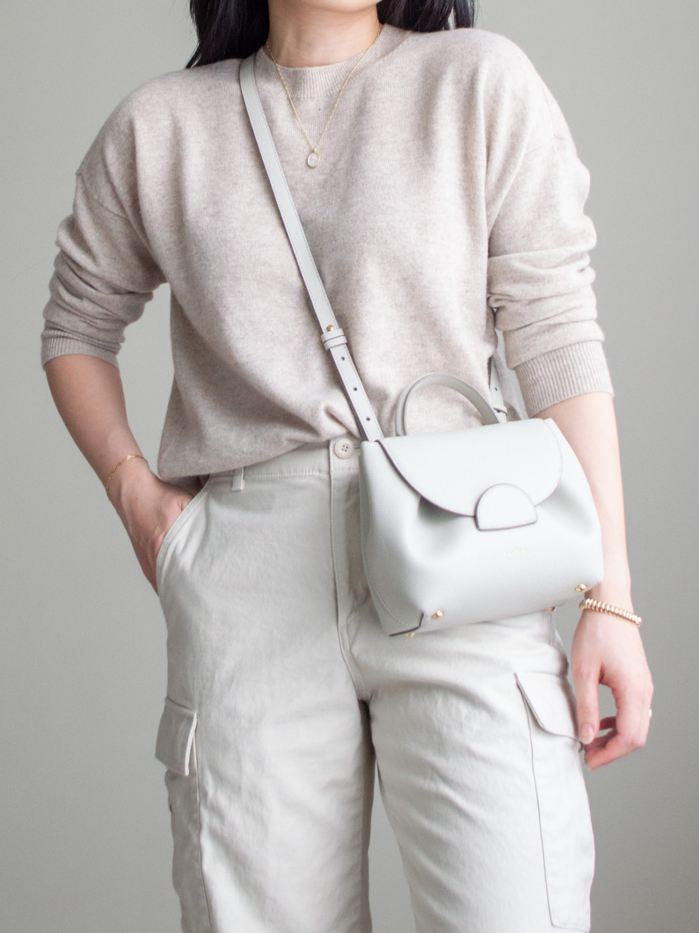 Close-up detailed outfit shot of Sharon of Her Simple Sole wearing a beige cashmere sweater, cream cargo pants, and an off-white crossbody bag | minimalist outfits | simple outfit ideas | casual fall outfit